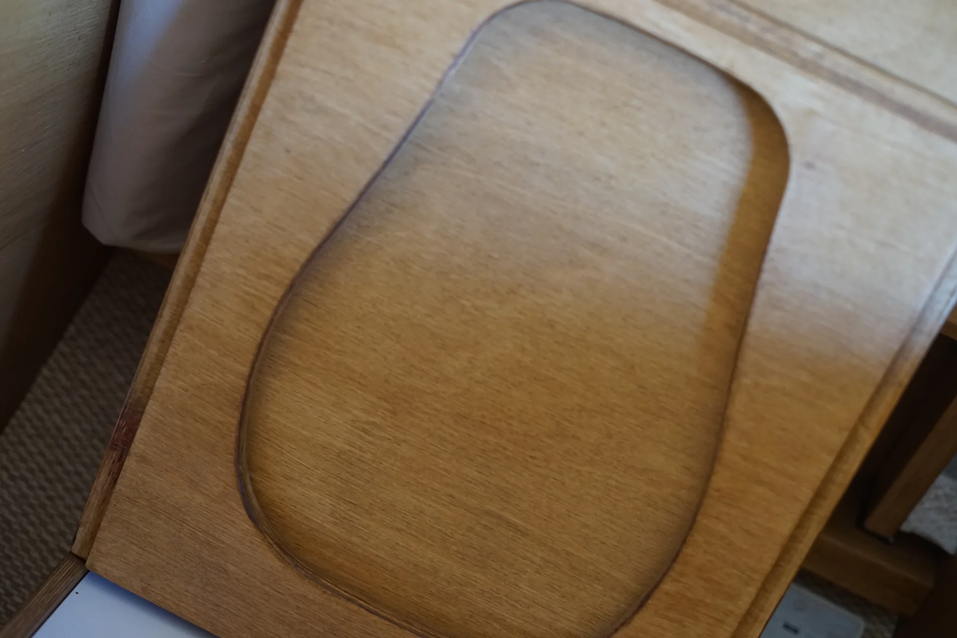 Abattant en contreplaqué verni des toilettes sèches fermé, découpe affleurante et finition vernie