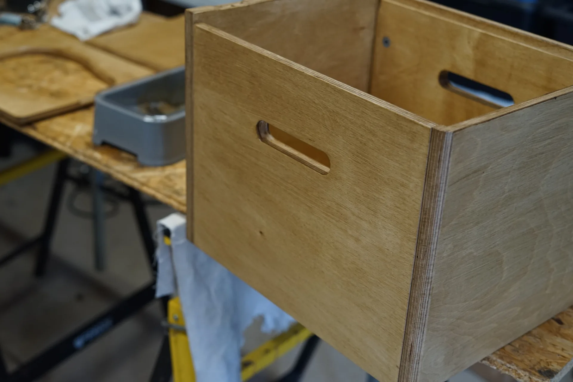 Caisson de toilettes sèches en contreplaqué bouleau en cours de fabrication sur l'établi de l'atelier, poignées découpées sur les flancs