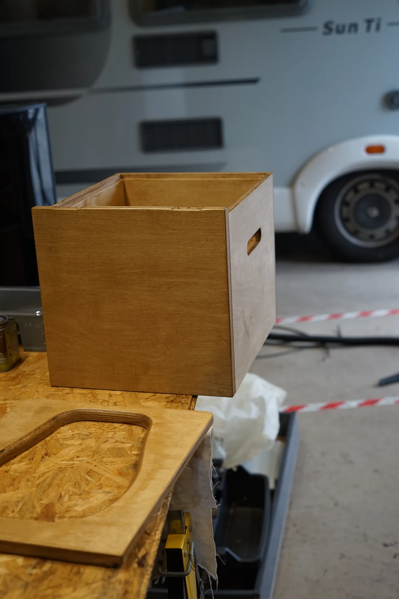 Caisson de toilettes sèches en contreplaqué posé devant un camping-car intégral dans l'atelier d'Anglet